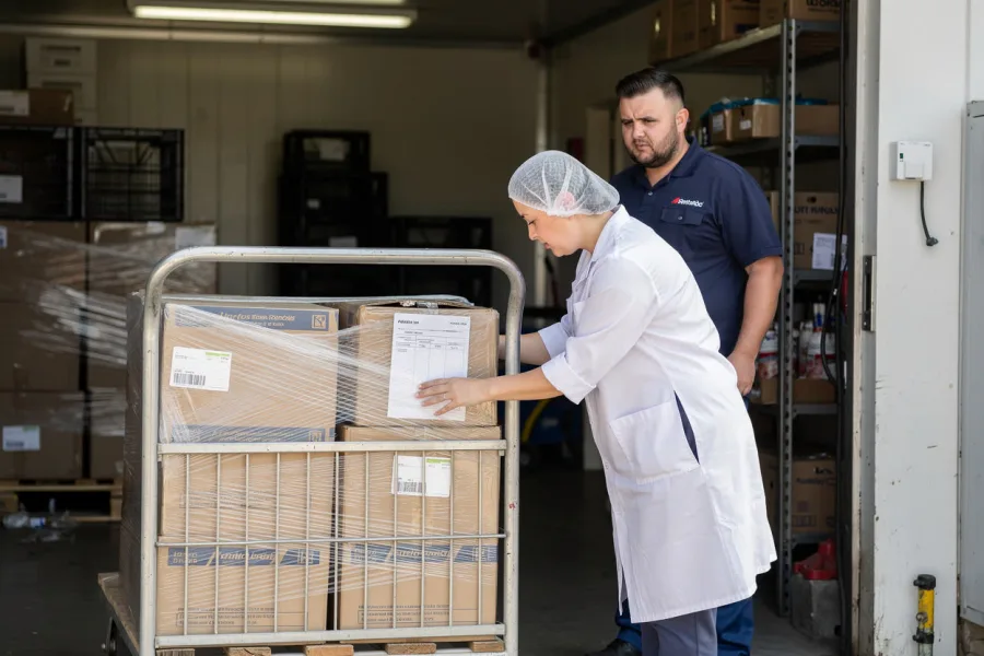 A worker unloads boxes from a trolley in a shop stockroom