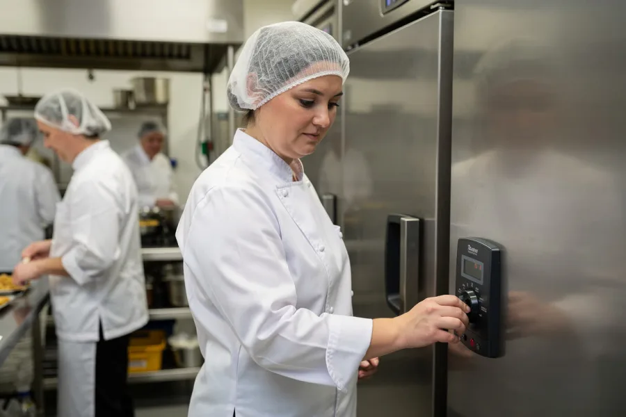 A chef uses a keypad on a fridge door