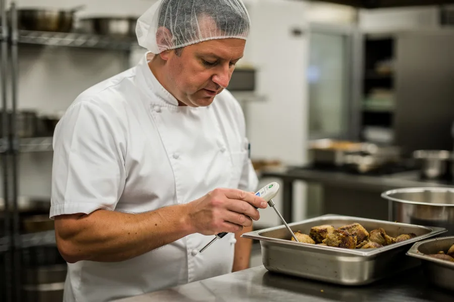 A chef checks a tray of cooked food